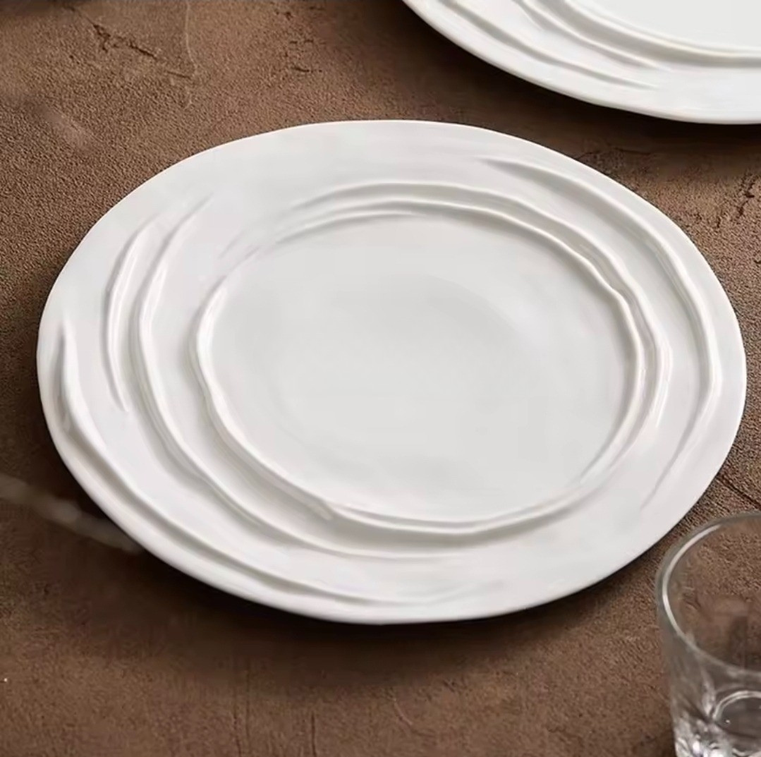 Ripple-edge porcelain dinner plates in 26cm and 31cm sizes, styled with elegant food plating on a brown linen tablecloth.